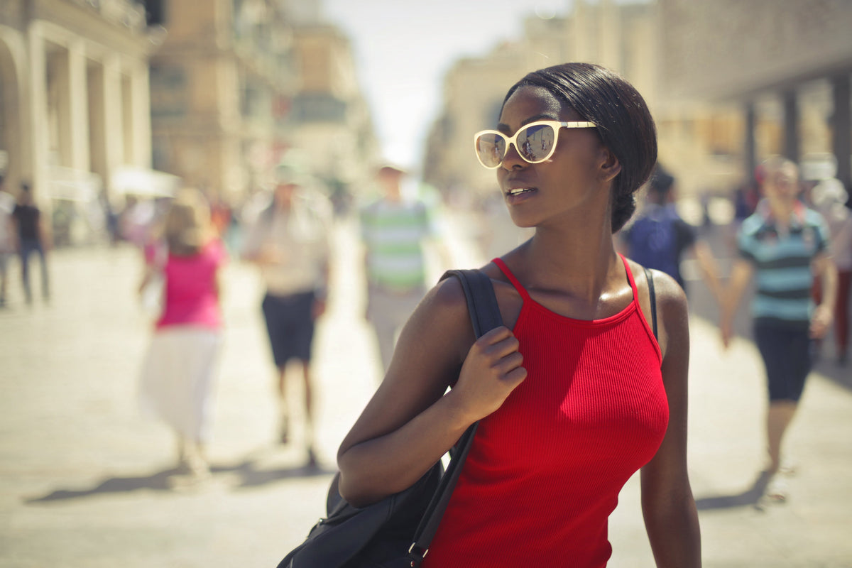Woman wearing red top and white sunglasses walking in the city
