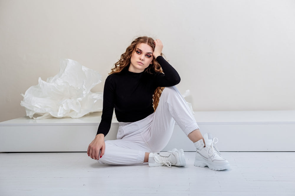 Woman sitting down wearing white pants