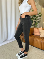 Person wearing black pants and white sneakers in a living room setting