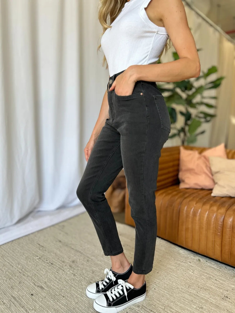 Person wearing black pants and white sneakers in a living room setting