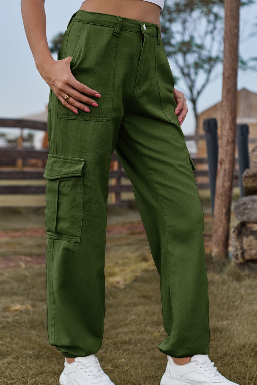 Person wearing green cargo pants standing outdoors with a rustic background.