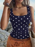 Woman wearing a navy blue polka dot top with a blurred background