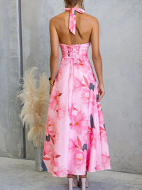 Woman wearing a pink floral dress with a gray wall and potted plant in the background