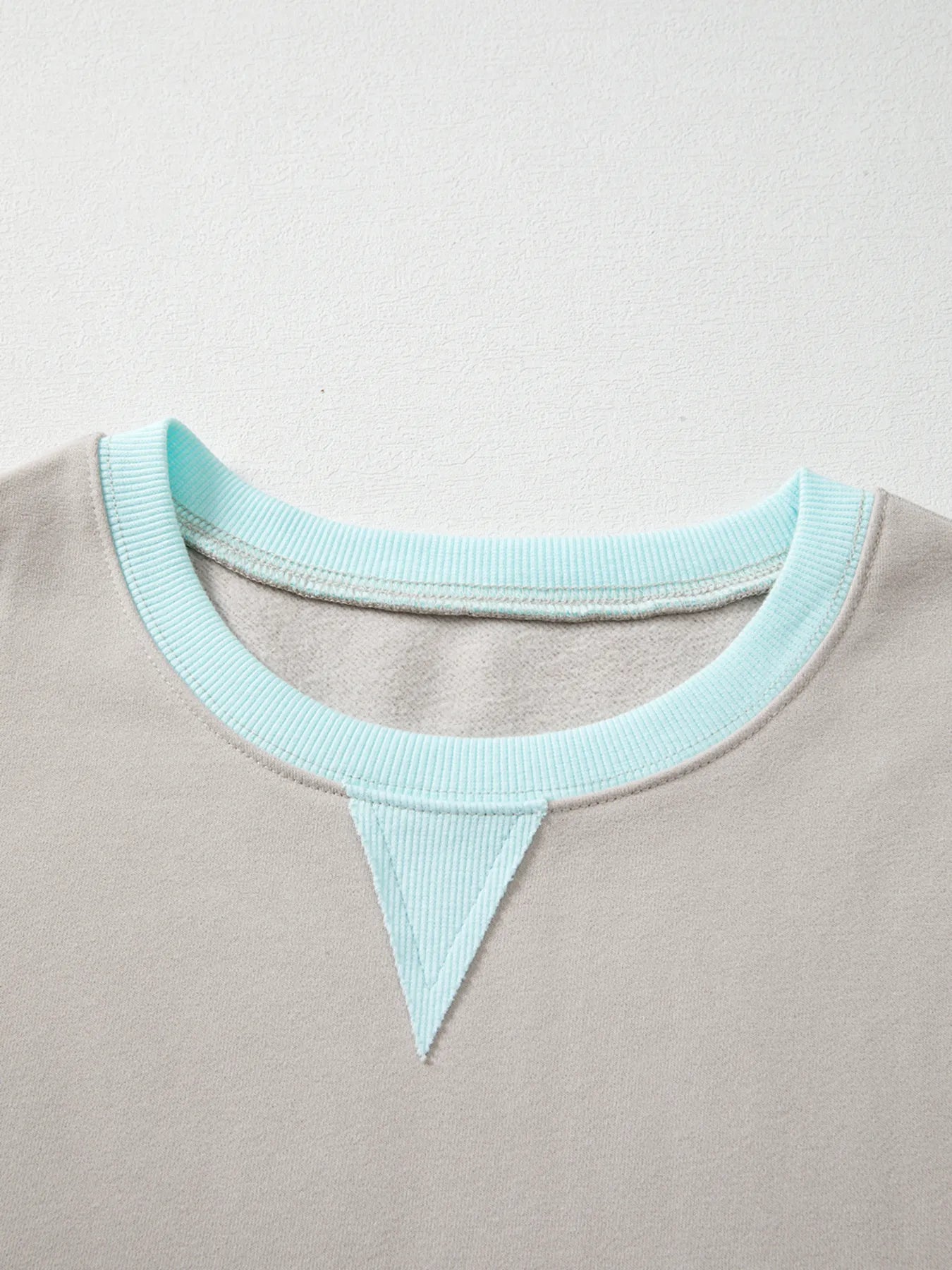 Close-up of a gray garment with a light blue neckline on a light gray background
