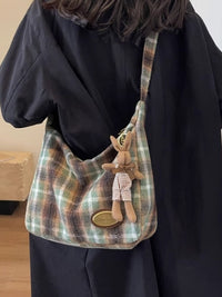 Plaid handbag with a plush toy rabbit attached, worn by a person.