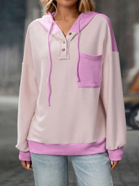 Person wearing a light pink and purple hoodie with a blurred background