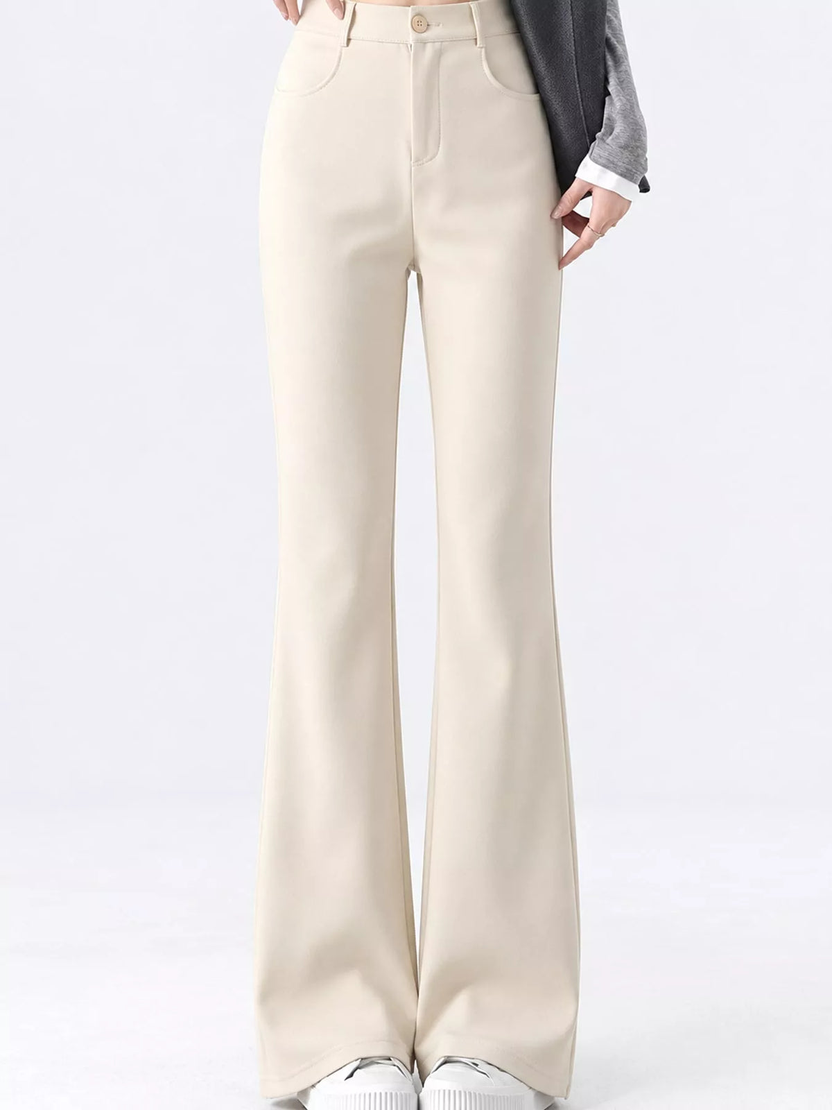 A person wearing high-waisted, light beige wide-leg pants with a gray blazer and white sneakers, shown from the waist down against a plain white studio background.