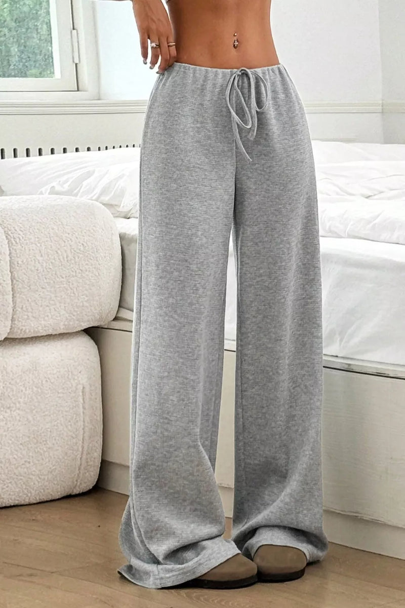 Person wearing gray wide-leg pants in a living room setting