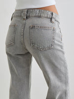 Gray jeans being worn on a plain background