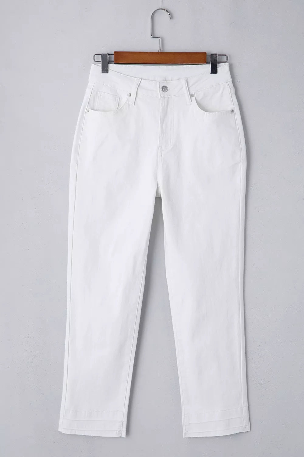 White jeans on a hanger against a gray background