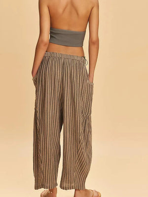 Woman wearing a strapless top and striped pants on a beige background