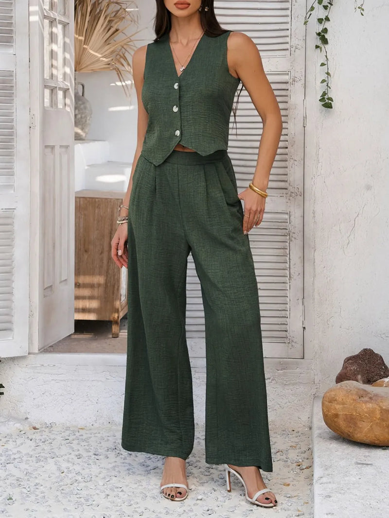 Woman wearing a green vest and wide-leg pants in an indoor setting.