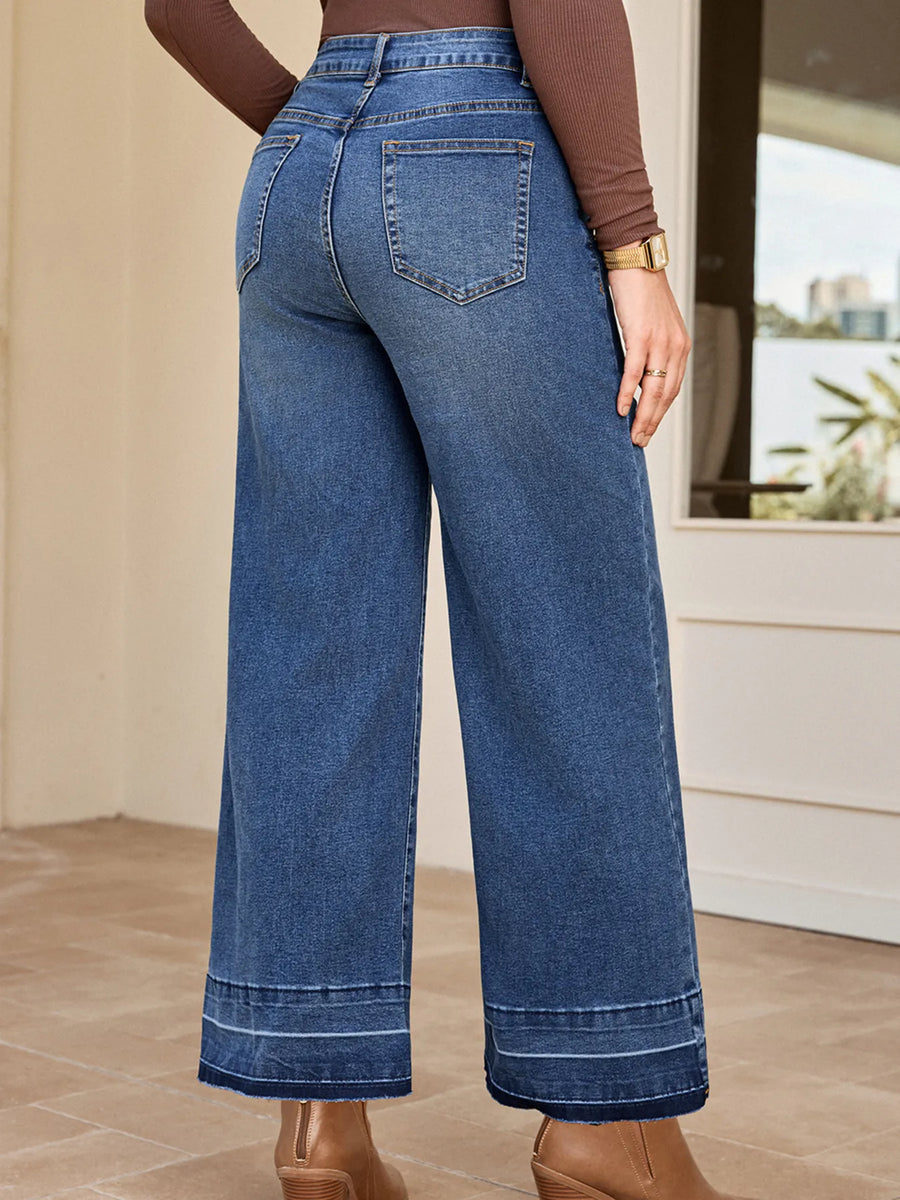 Person wearing blue wide-leg jeans in a room with a neutral background