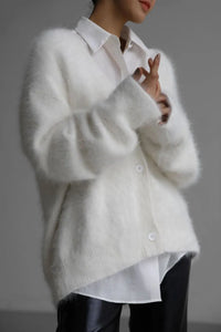 White fluffy cardigan over a white shirt with a blurred background