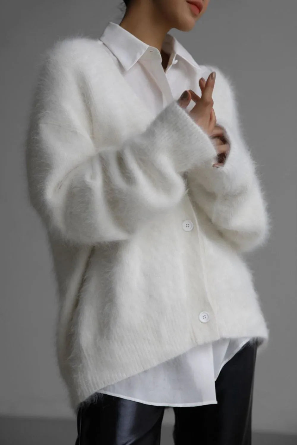 White fluffy cardigan over a white shirt with a blurred background