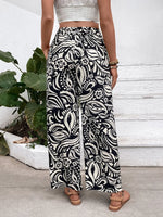 Person wearing black and white patterned pants with a white wall and plant in the background