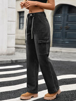 Person wearing black cargo pants and tan boots on a city street.