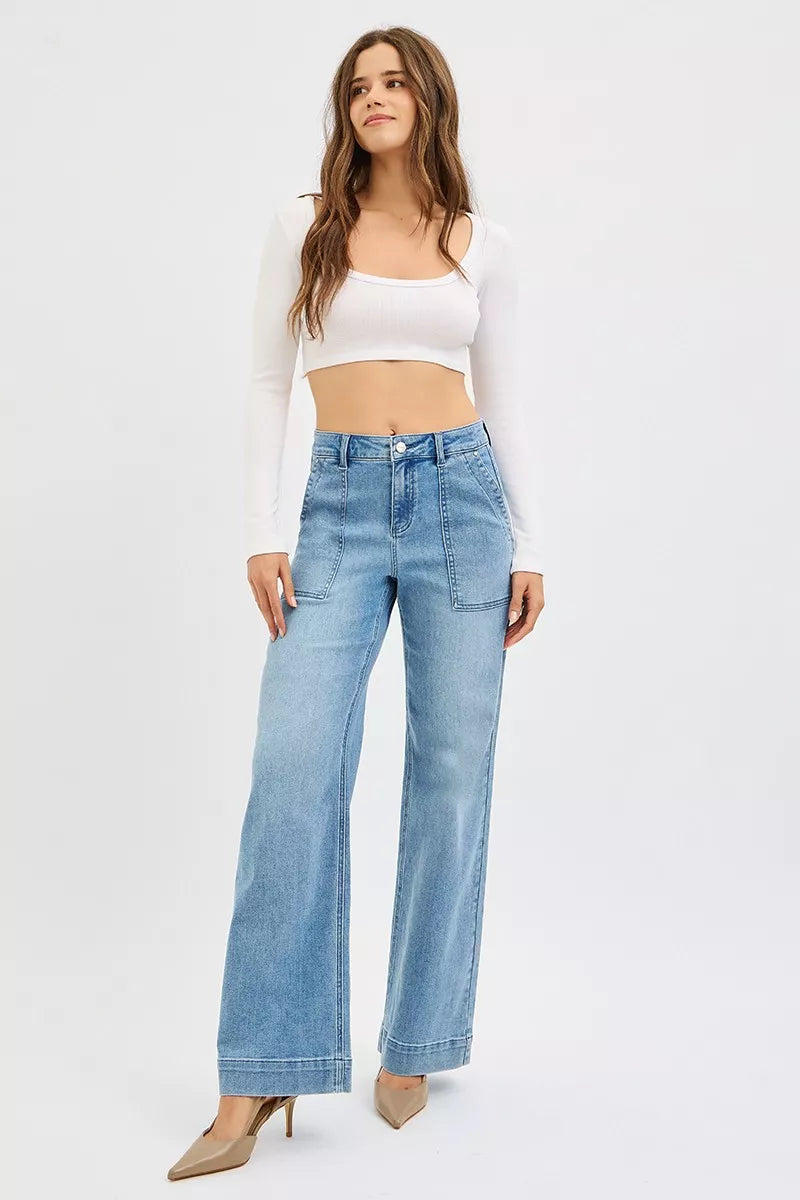 Woman wearing light blue jeans and a white top on a white background