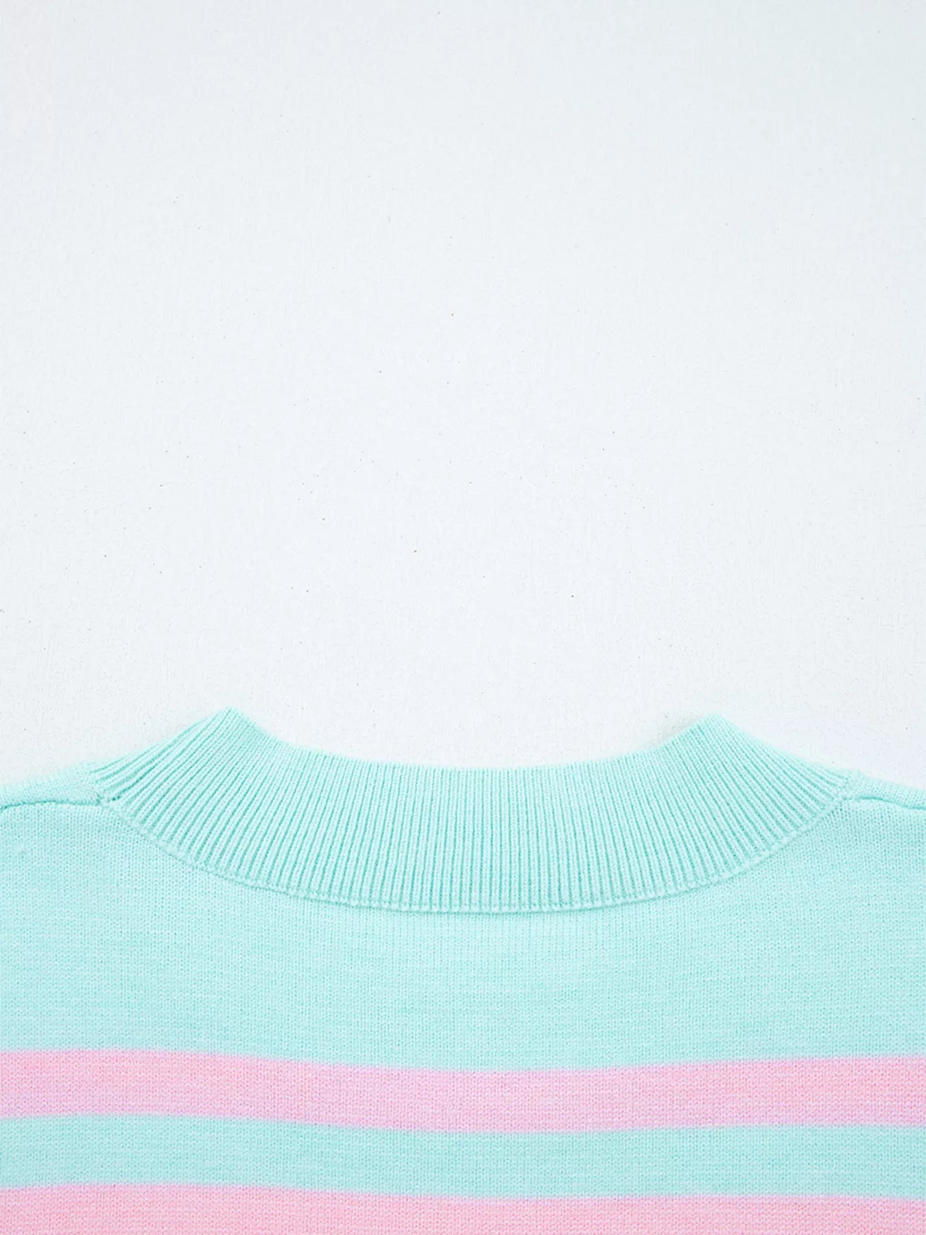 Close-up of a light blue sweater with a pink stripe on a white background