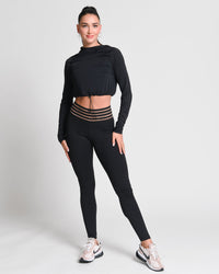 Woman wearing a black long-sleeve top and leggings on a white background