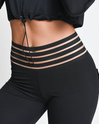 Black leggings with sheer stripes on a plain background