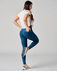 Woman wearing blue jeans and a white top on a gray background