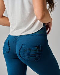 Person wearing blue jeans with distressed details on a plain background