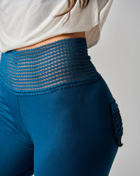 Blue leggings with textured waistband worn by a person on a plain background