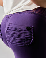 Purple leggings with a heart logo on a plain background