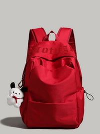 Red backpack with a small white plush toy on a gray background