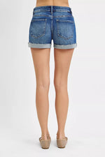 Blue denim shorts worn by a person on a white background