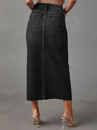 Person wearing a black denim skirt against a gray background