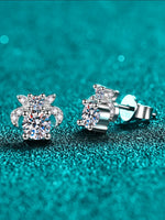Silver stud earrings with clear gemstones on a teal glittery background