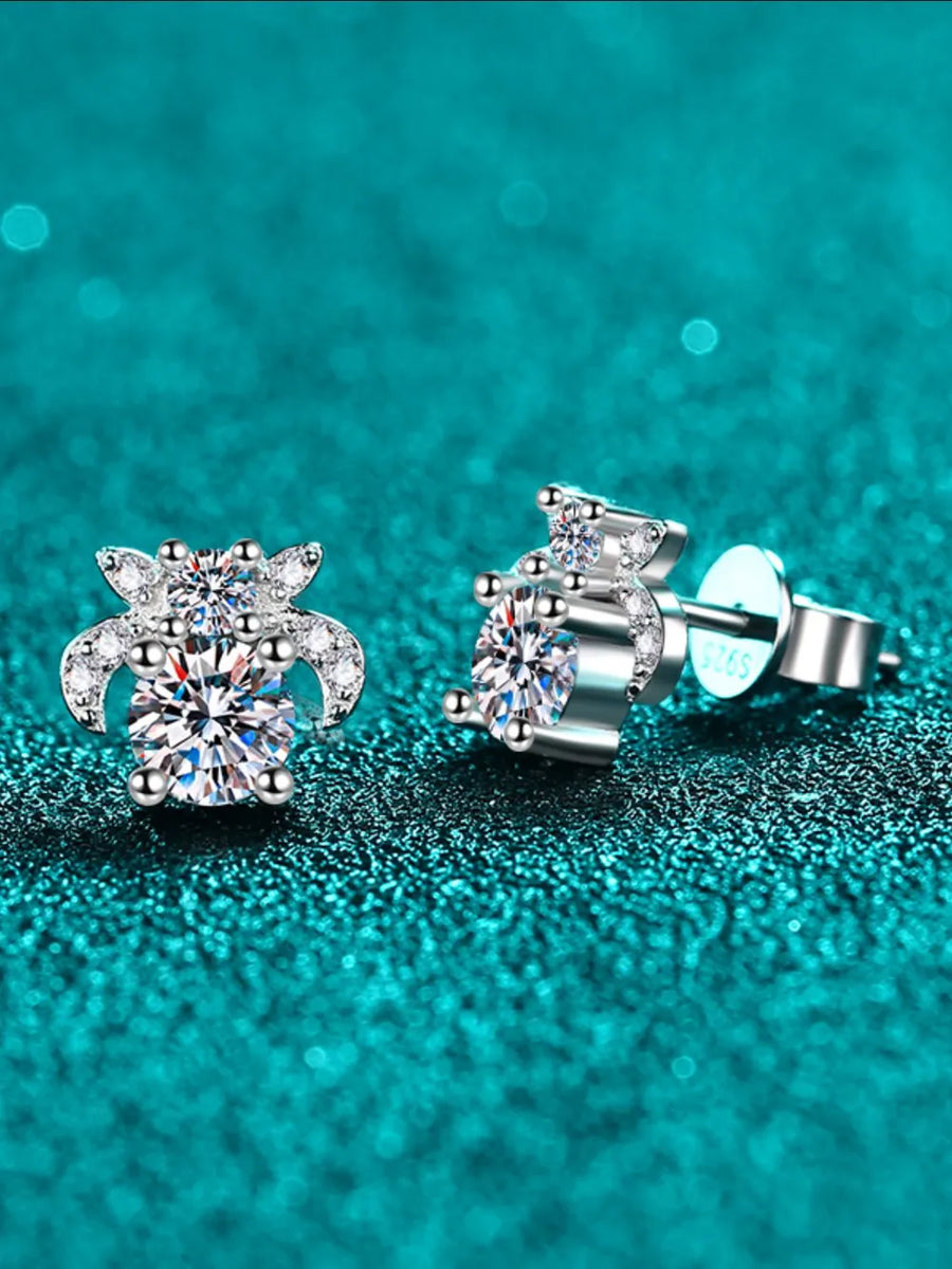 Silver stud earrings with clear gemstones on a teal glittery background