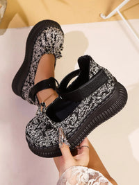 Black and white patterned slip-on shoes with a person wearing them on a light background