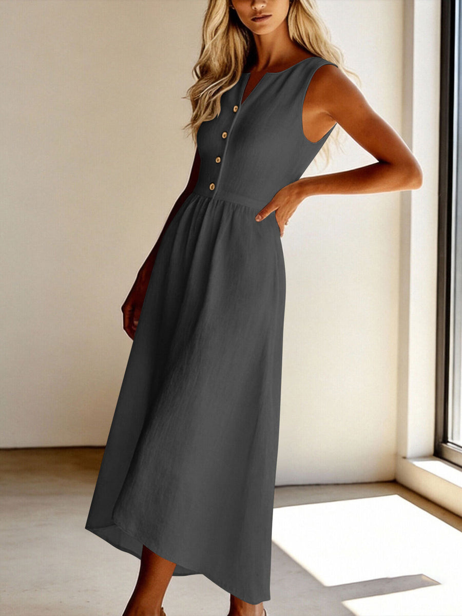Woman wearing a gray sleeveless dress with buttons in a bright room.