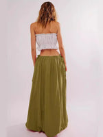 Woman wearing a white strapless top and green skirt on a light pink background