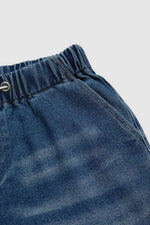 Close-up of blue denim shorts with a button on a light gray background