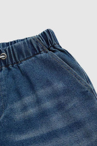 Close-up of blue denim shorts with a button on a light gray background