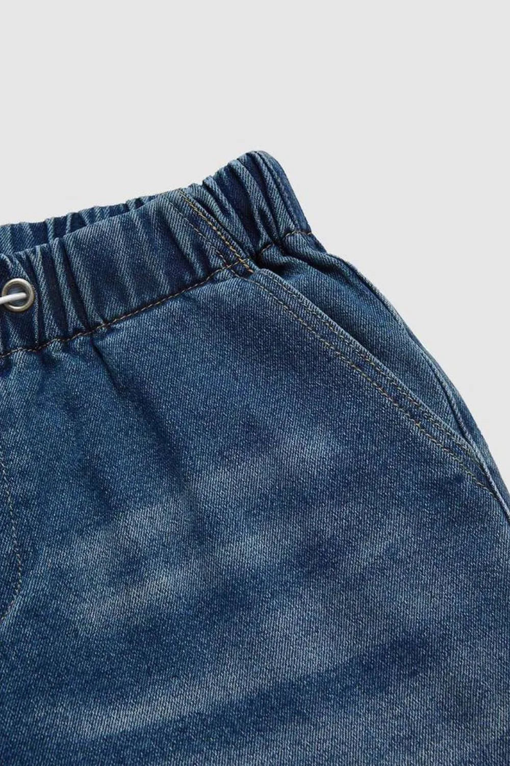 Close-up of blue denim shorts with a button on a light gray background