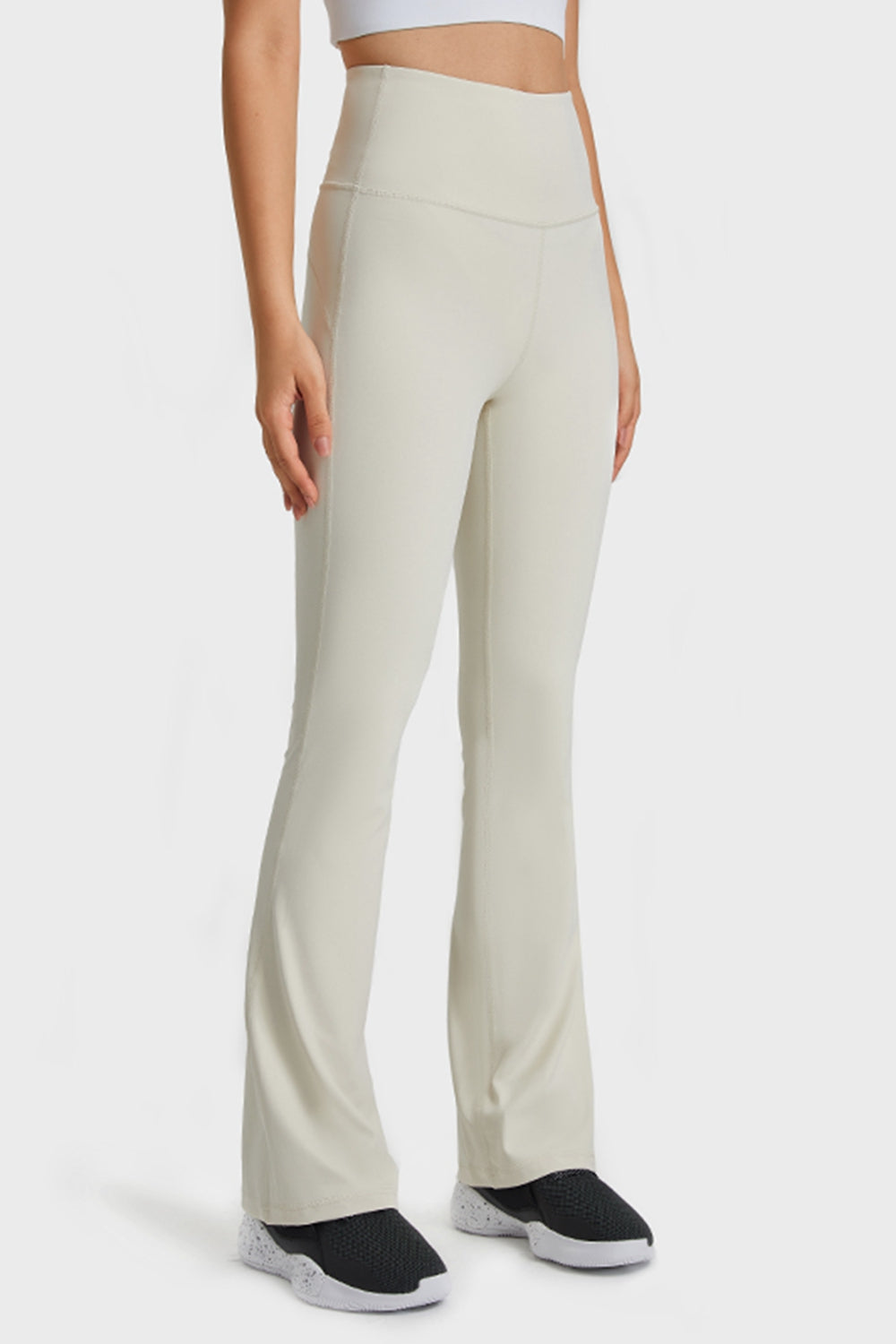 Person wearing beige high-waisted pants on a white background