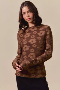 Woman wearing a brown floral patterned top against a beige background