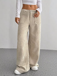 Person wearing beige corduroy wide-leg pants with a plain background