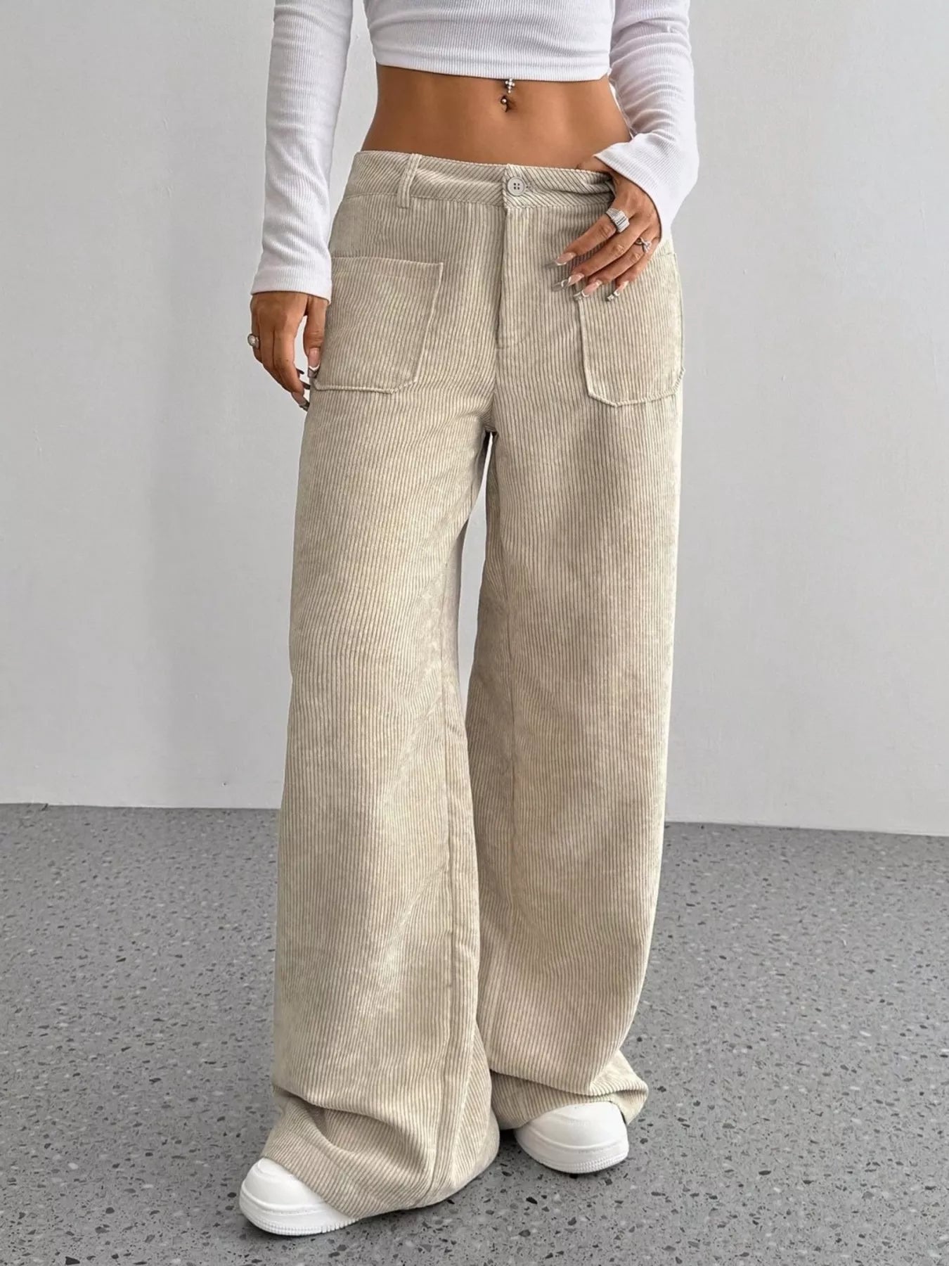 Person wearing beige corduroy wide-leg pants with a plain background