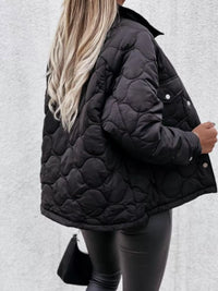 Person wearing a black quilted jacket against a light gray background