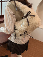 Person wearing a fluffy beige vest with black ribbons indoors.