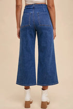 Person wearing blue denim wide-leg jeans on a beige background