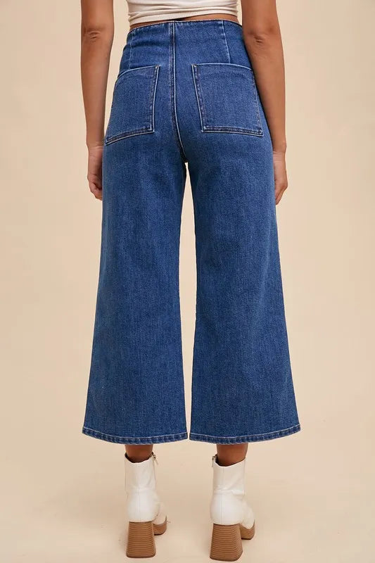 Person wearing blue denim wide-leg jeans on a beige background