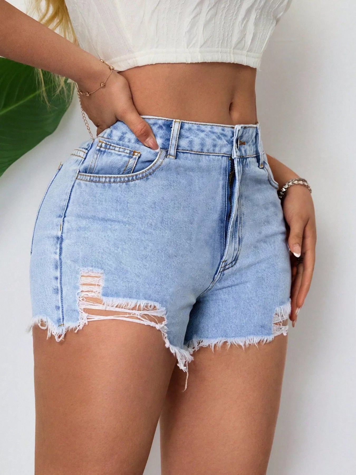 Person wearing light blue denim shorts with a white top against a neutral background