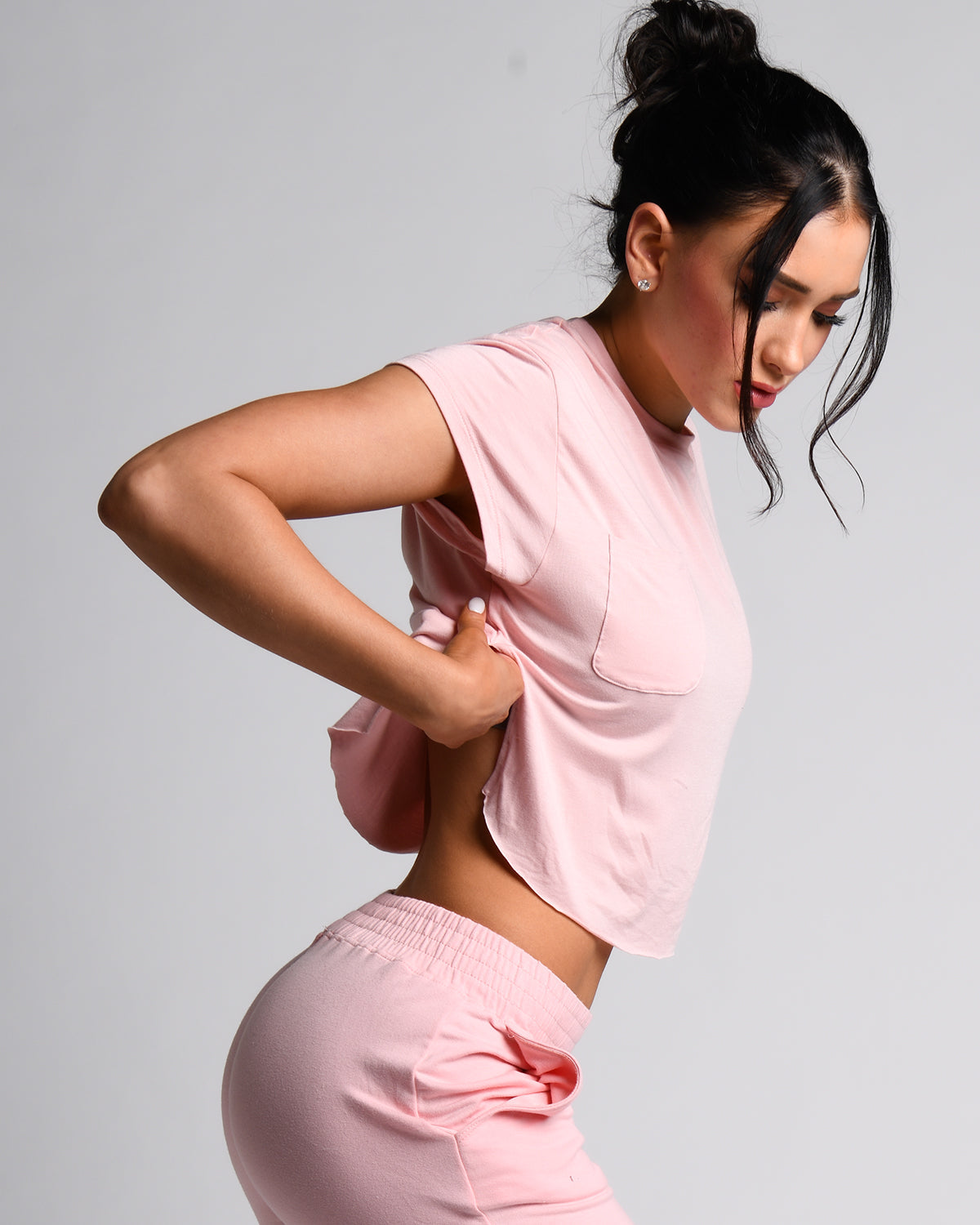 A person wearing a pink t-shirt with a front right pocket, paired with matching pink shorts.